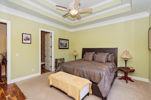 bedroom featuring connected bathroom, ceiling fan, a raised ceiling, ornamental molding, and hardwood / wood-style flooring