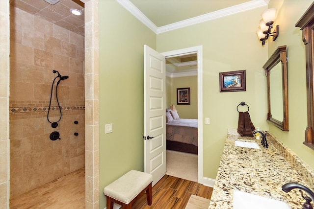 bathroom with tiled shower, hardwood / wood-style floors, vanity, and ornamental molding