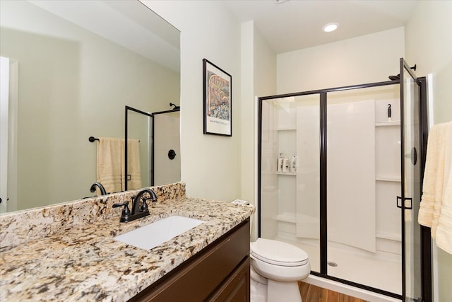 bathroom featuring vanity, hardwood / wood-style flooring, toilet, and a shower with shower door