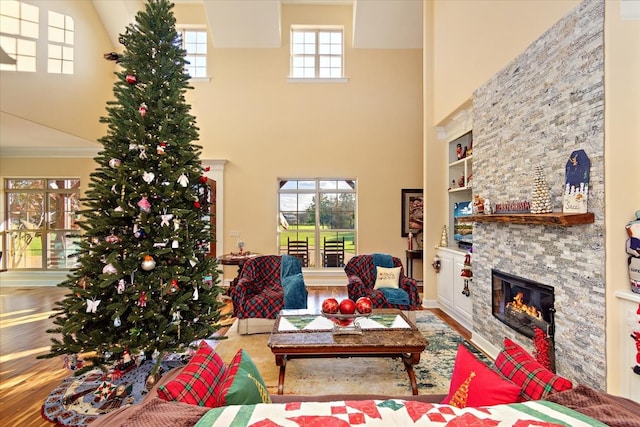 living room with a high ceiling, a stone fireplace, and built in shelves