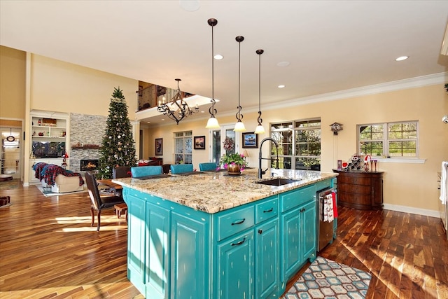 kitchen featuring a fireplace, sink, a kitchen island with sink, and dark wood-type flooring