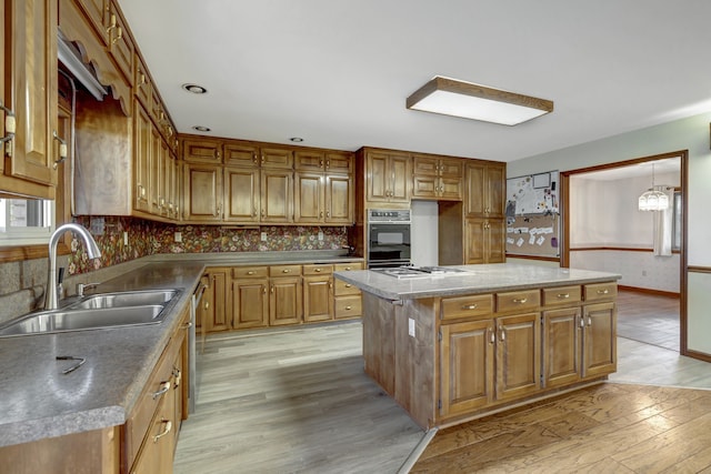 kitchen featuring sink, light hardwood / wood-style floors, a kitchen island, stainless steel appliances, and a chandelier