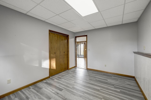 empty room with a drop ceiling and light hardwood / wood-style floors