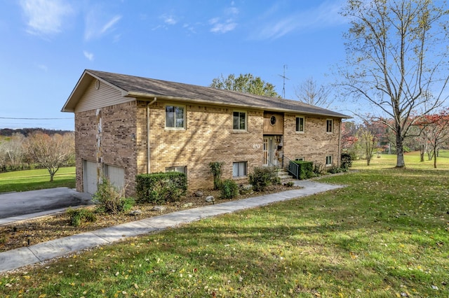 bi-level home featuring a garage, brick siding, driveway, and a front lawn