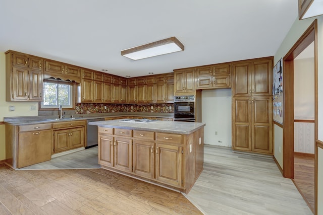 kitchen with white gas cooktop, a sink, stainless steel dishwasher, a center island, and light wood finished floors