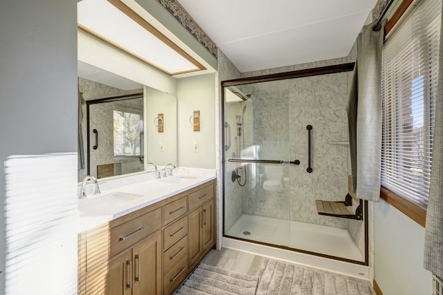 full bath featuring double vanity, a stall shower, and a sink