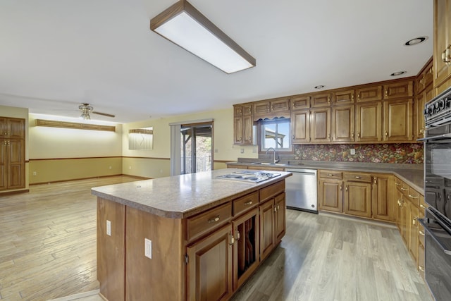 kitchen with stainless steel dishwasher, ceiling fan, a center island, and light hardwood / wood-style floors