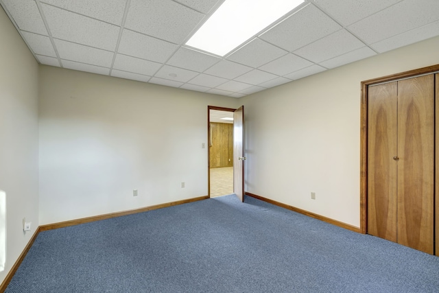 unfurnished bedroom featuring carpet, a paneled ceiling, and a closet