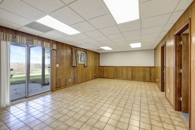 empty room with a paneled ceiling and wooden walls