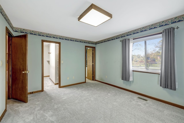 unfurnished bedroom featuring baseboards, visible vents, and light colored carpet