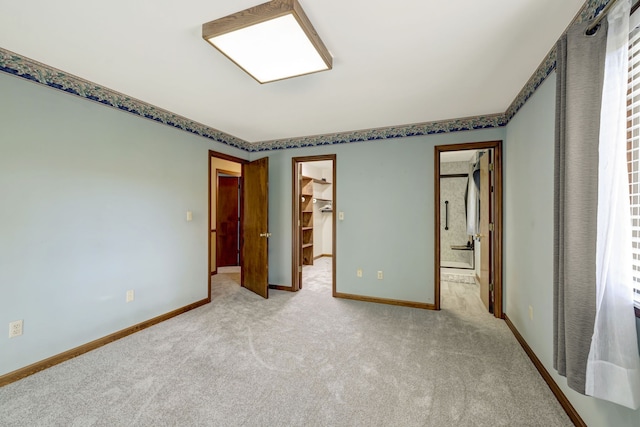 unfurnished bedroom featuring a spacious closet, a closet, and light colored carpet