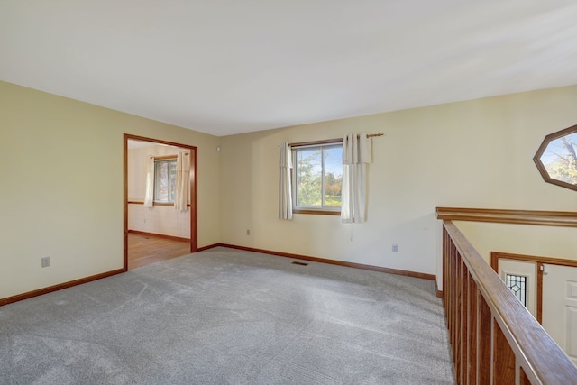 carpeted spare room featuring visible vents and baseboards