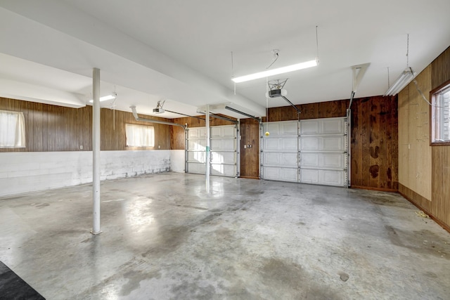 garage with a garage door opener and wood walls