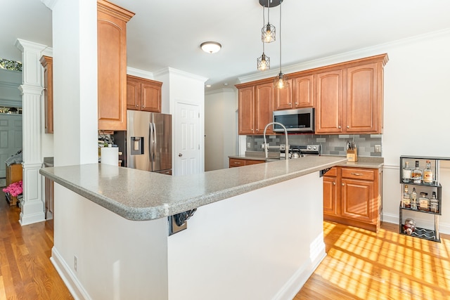 kitchen featuring crown molding, light hardwood / wood-style flooring, tasteful backsplash, decorative light fixtures, and stainless steel appliances