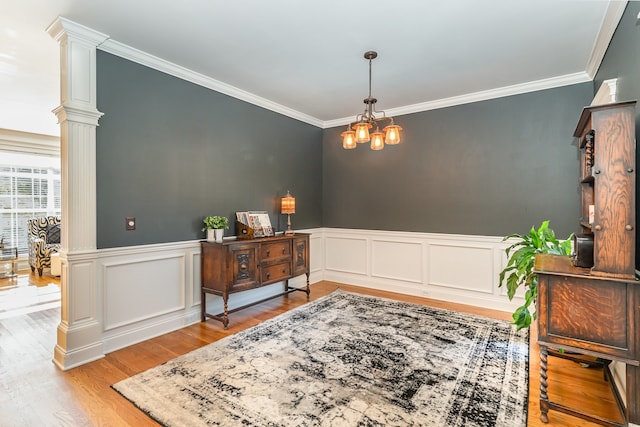 interior space featuring an inviting chandelier, decorative columns, crown molding, and light hardwood / wood-style floors