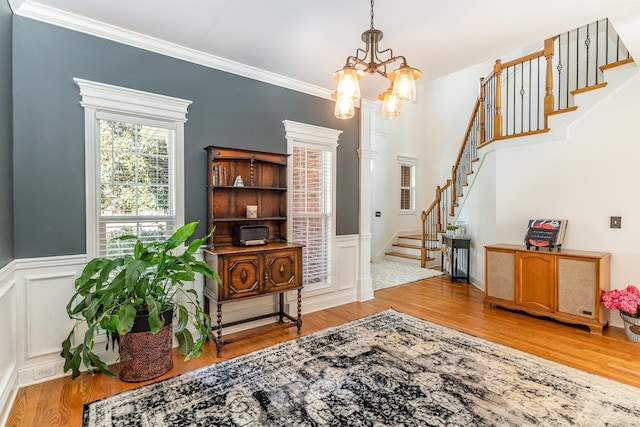 foyer with crown molding, a notable chandelier, and light wood-type flooring