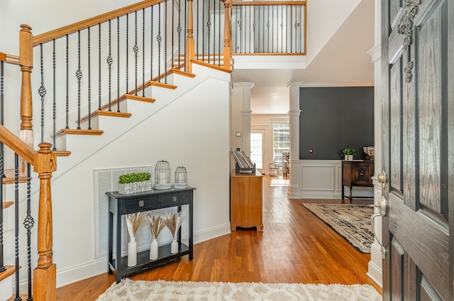 entrance foyer featuring hardwood / wood-style flooring, crown molding, and decorative columns