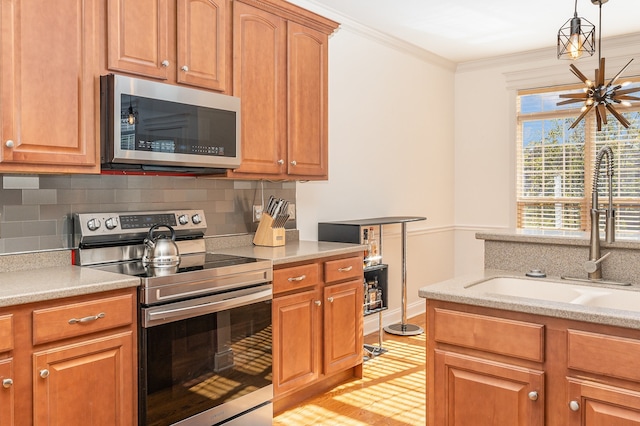 kitchen with backsplash, ornamental molding, stainless steel appliances, sink, and hanging light fixtures