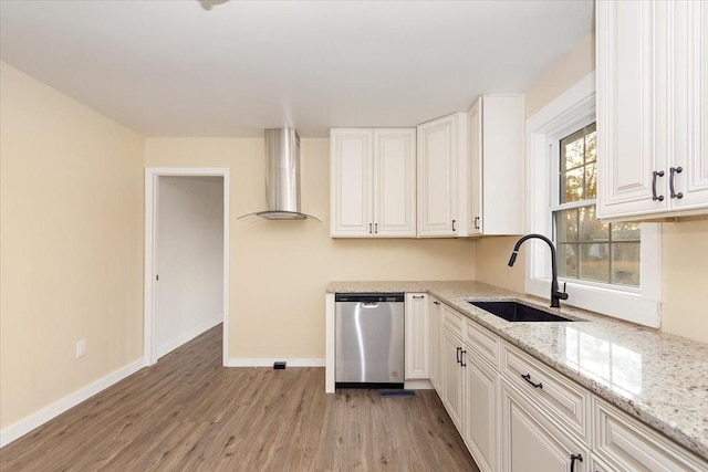 kitchen featuring light wood-type flooring, stainless steel dishwasher, wall chimney exhaust hood, sink, and white cabinets