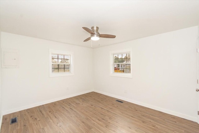 spare room featuring ceiling fan, electric panel, and light hardwood / wood-style flooring