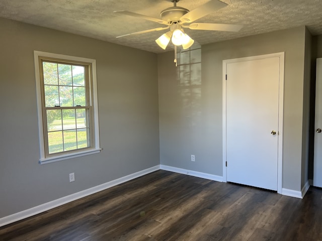 spare room with a textured ceiling, ceiling fan, and dark wood-type flooring