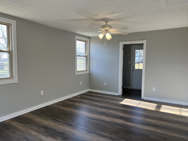 unfurnished room with dark hardwood / wood-style floors, a textured ceiling, and a wealth of natural light