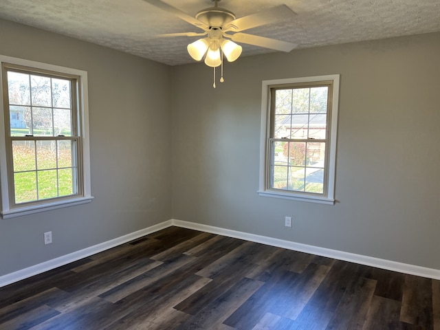 spare room with dark hardwood / wood-style flooring, ceiling fan, and a healthy amount of sunlight