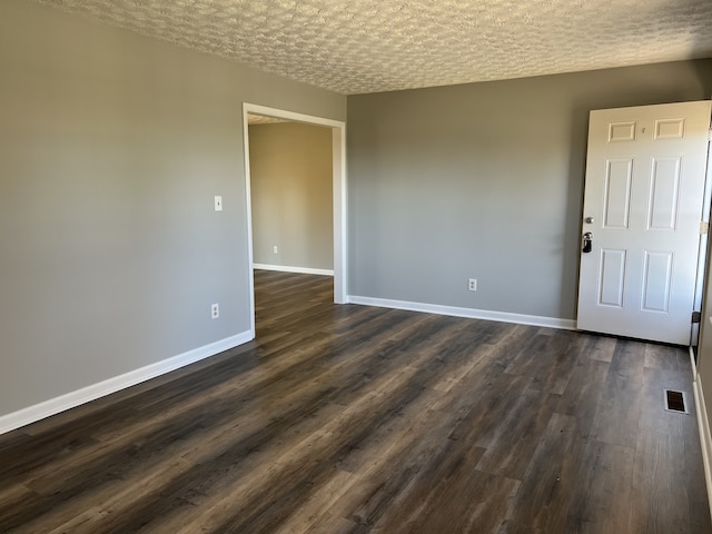 unfurnished room with a textured ceiling and dark hardwood / wood-style floors