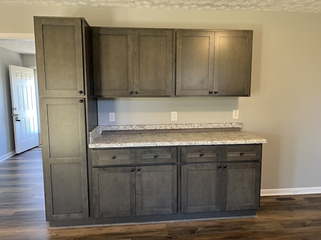 kitchen with dark hardwood / wood-style floors, dark brown cabinetry, and a textured ceiling