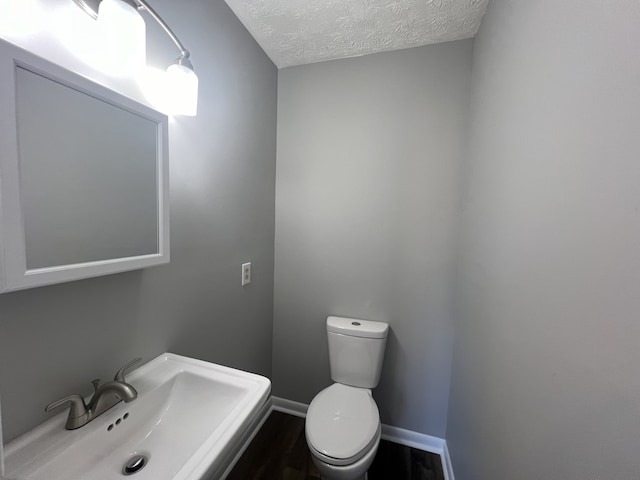 bathroom with a textured ceiling, toilet, and sink