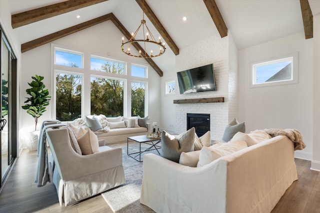 living room with hardwood / wood-style flooring, high vaulted ceiling, beamed ceiling, a fireplace, and a chandelier