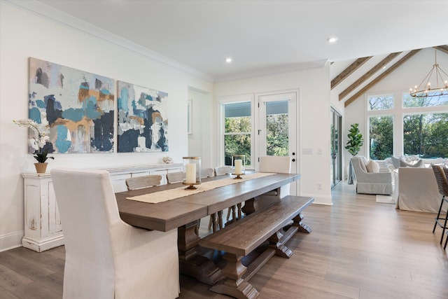 dining room featuring hardwood / wood-style floors, lofted ceiling with beams, a wealth of natural light, and a chandelier