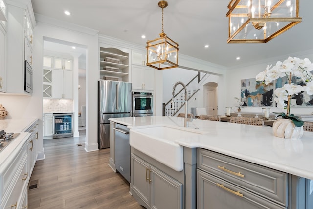 kitchen featuring white cabinetry, hanging light fixtures, wine cooler, gray cabinets, and appliances with stainless steel finishes