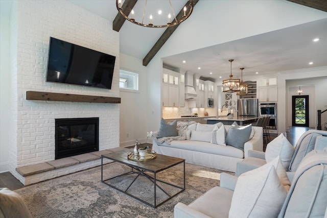 living room with vaulted ceiling with beams, a wealth of natural light, a fireplace, and a notable chandelier