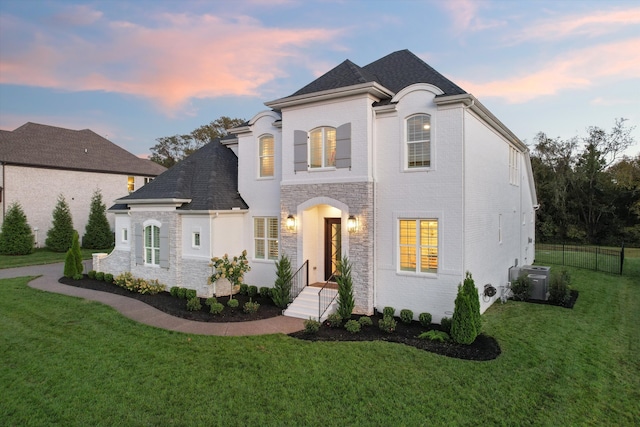 french country home with central AC unit and a yard