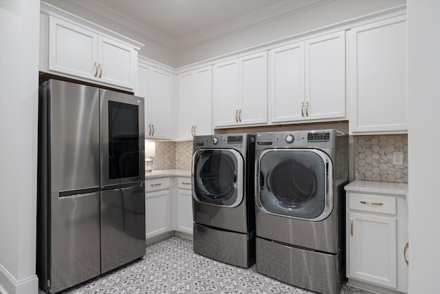 clothes washing area featuring cabinets, washing machine and dryer, and ornamental molding