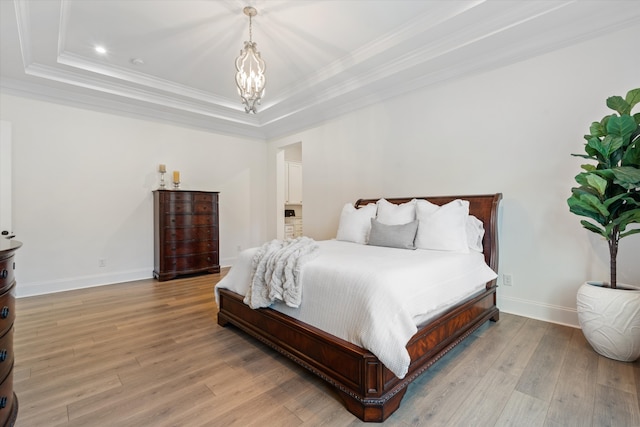 bedroom with a raised ceiling, a chandelier, ornamental molding, and light wood-type flooring