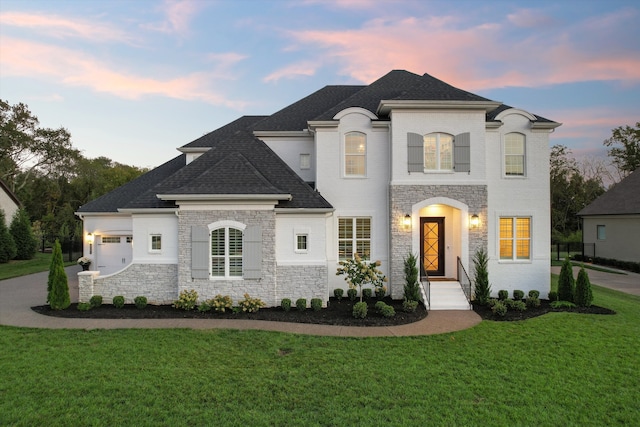 french country inspired facade with a yard and a garage