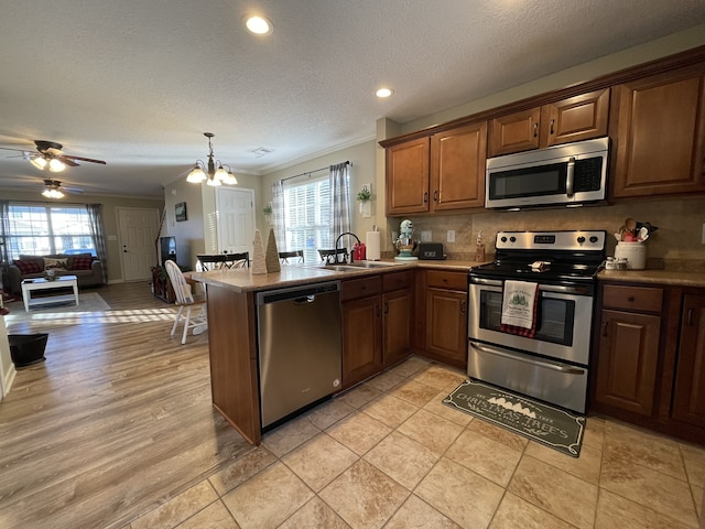 kitchen featuring kitchen peninsula, crown molding, plenty of natural light, and appliances with stainless steel finishes