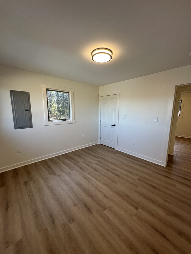 unfurnished bedroom with electric panel and dark hardwood / wood-style floors