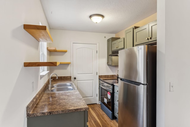 kitchen with dark hardwood / wood-style flooring, a textured ceiling, stainless steel appliances, sink, and green cabinetry