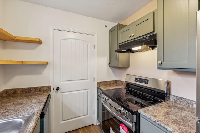 kitchen with sink, stainless steel stove, green cabinetry, light hardwood / wood-style flooring, and a textured ceiling