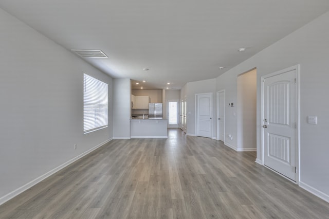 unfurnished living room with light hardwood / wood-style floors and a healthy amount of sunlight