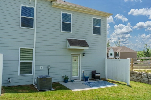 rear view of property featuring a yard, cooling unit, and a patio area