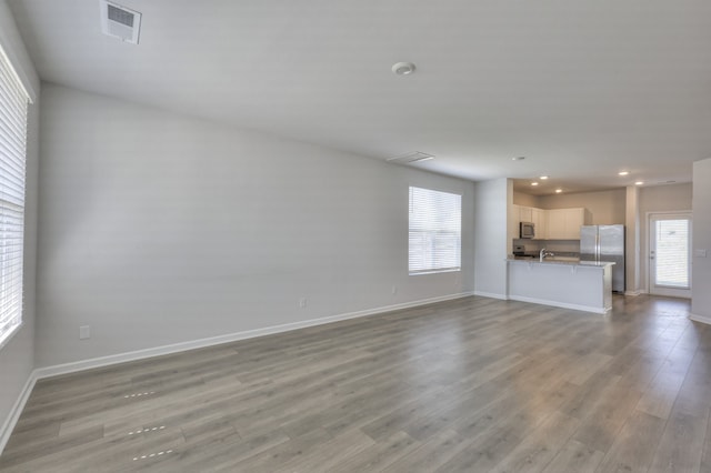 unfurnished living room featuring light wood-type flooring, plenty of natural light, and sink