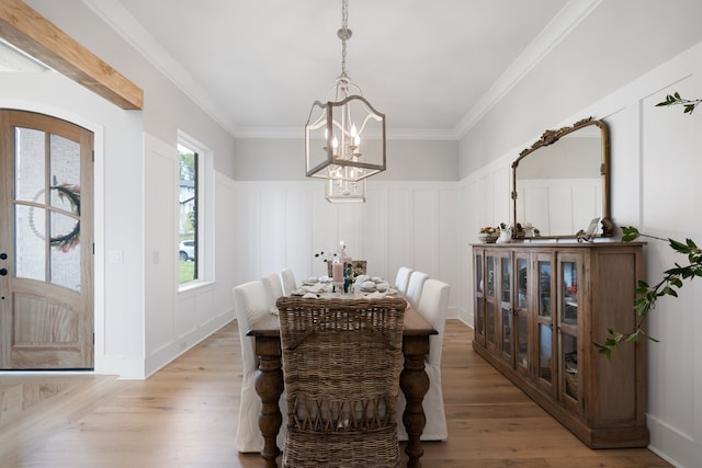 dining space with light hardwood / wood-style floors, crown molding, a healthy amount of sunlight, and a notable chandelier