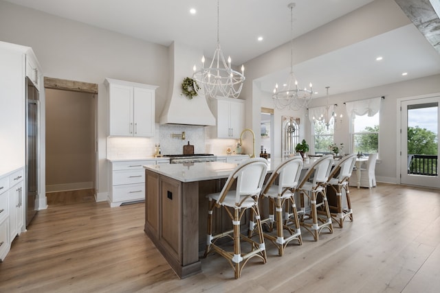 kitchen with white cabinetry, a large island, a kitchen breakfast bar, and light wood-type flooring