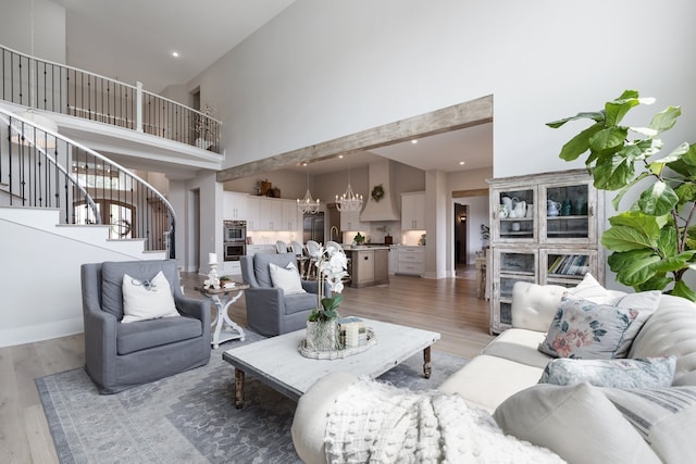 living room featuring a chandelier, wood-type flooring, and high vaulted ceiling