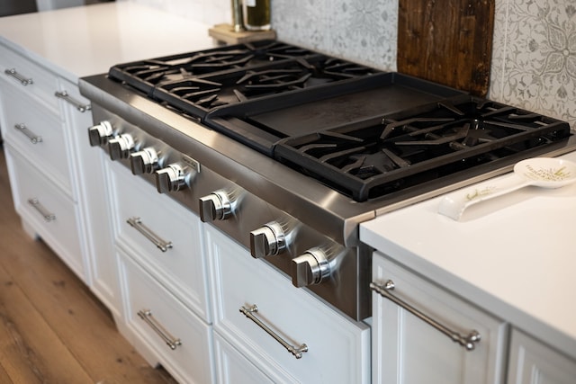 interior details with white cabinets, hardwood / wood-style flooring, and stainless steel stove