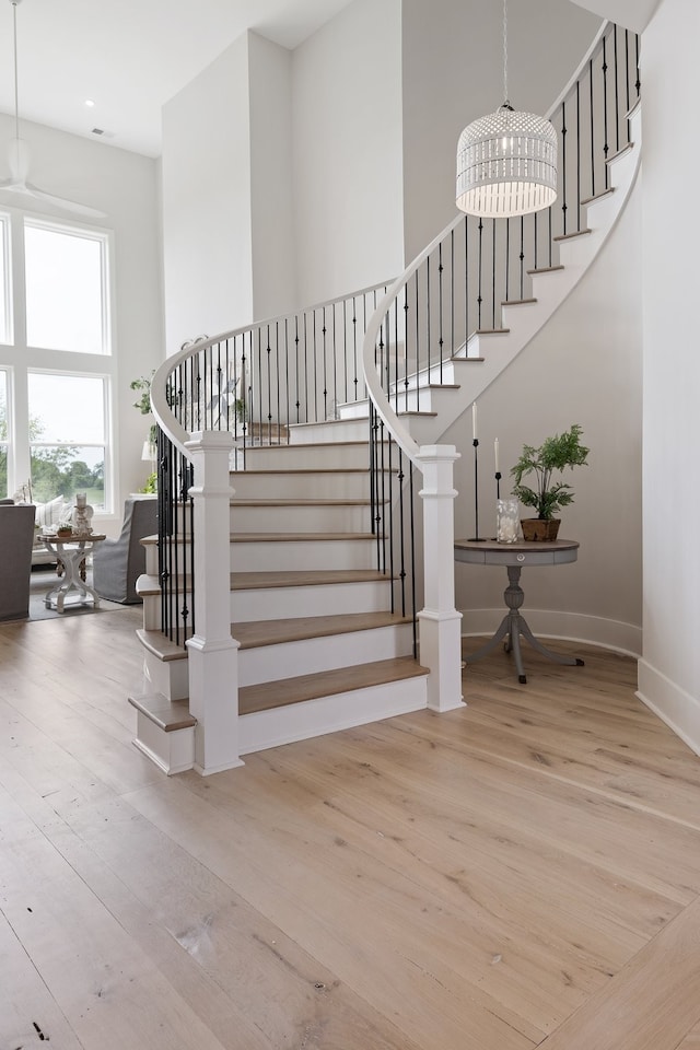 stairway with hardwood / wood-style floors, a chandelier, and a high ceiling